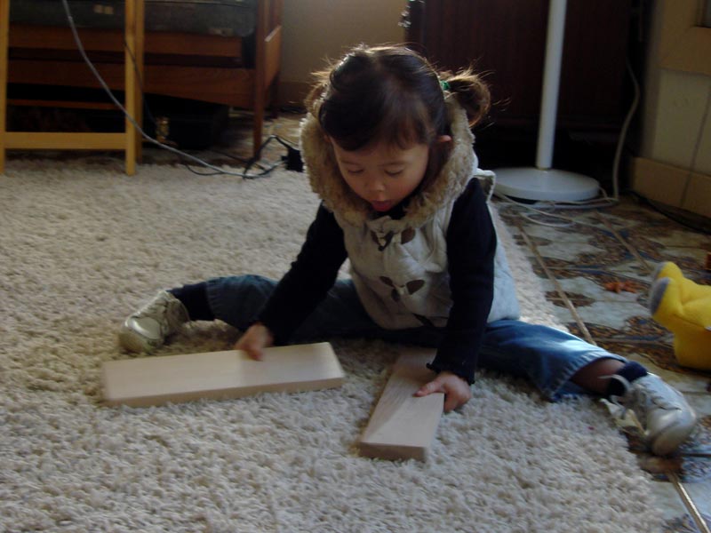 A young child playing with blocks while doing the splits.