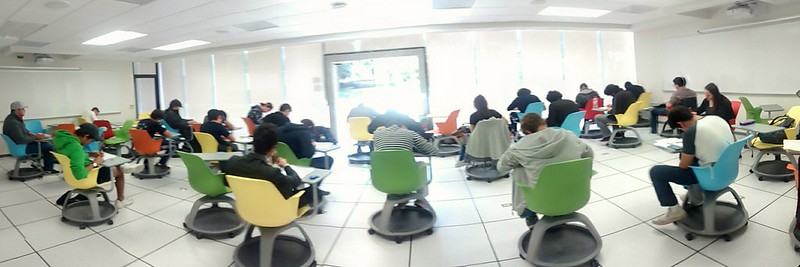 Students in colorful chairs applying an exam.