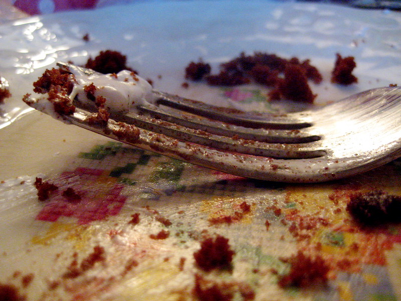 Close up of a fork on a plate that previously had a slice of birthday cake.