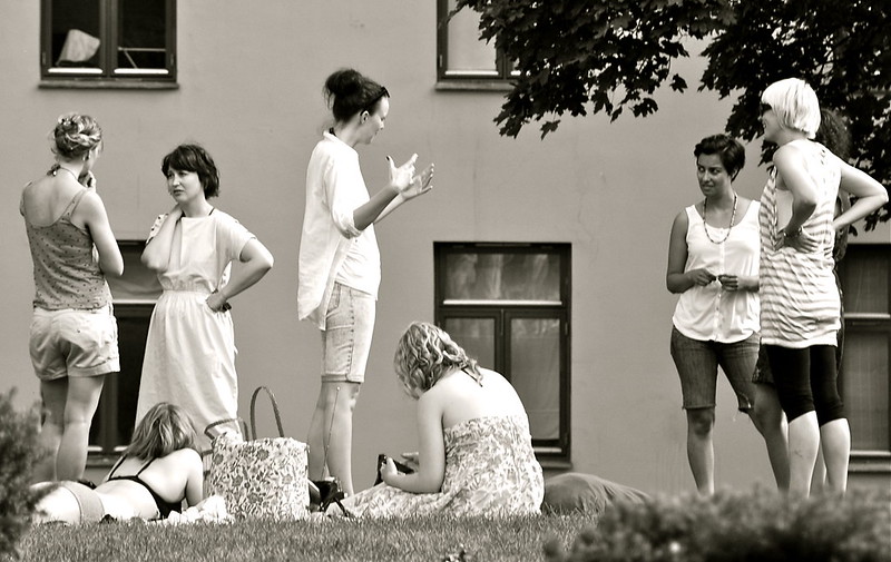 Black and white image with various conversations happening between small groups of people.