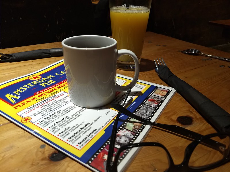 Picture of cofee on a breakfast menu with glasses in the foreground.