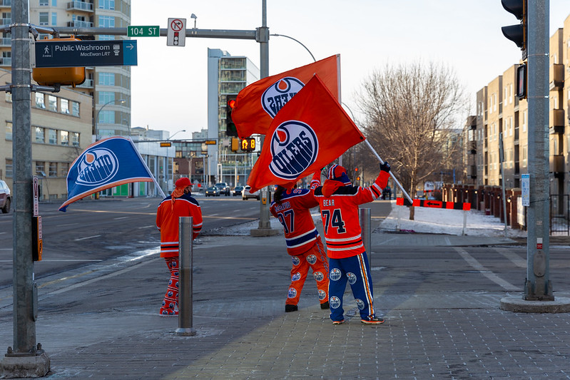 Three Edmonton Oilers fans near the rink in Oilers clothing and Oilers flags.