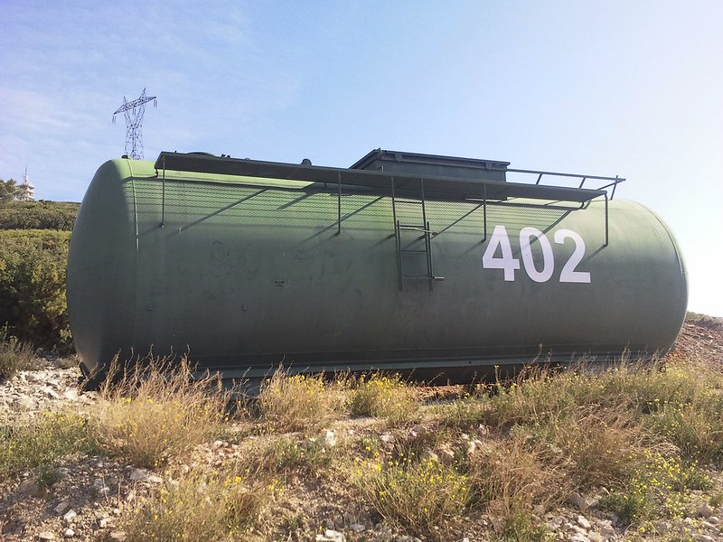 Image of a large green cistern tank with the number 402 somewhere in a field in the south of France.