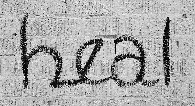 Close up of the word heal apparently painted on a grey brick wall.