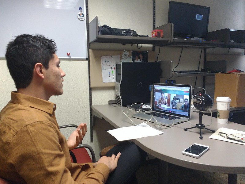 Student in an office in a Google Hangout using a laptop.