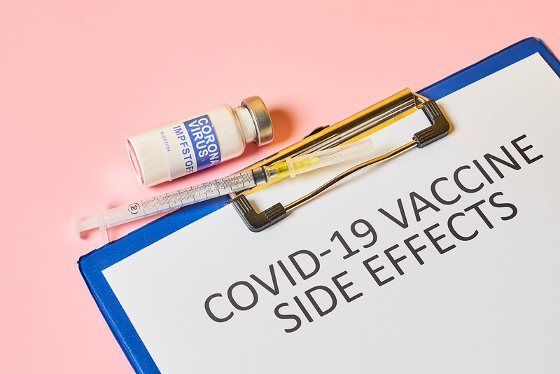 Picture of vaccine vial, injection needle and clipboard with the words "Covid-19 Vaccine Side Effects"