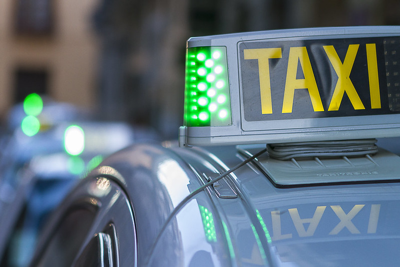 Close-up of at "TAXI" sign on top of a taxi cab.